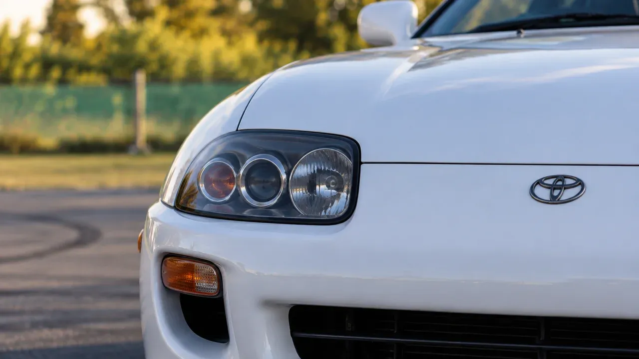 Close-up of the headlamp and front bodywork of a white Toyota Supra A80