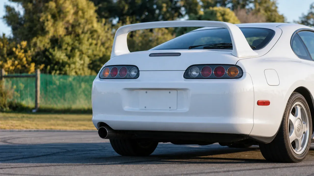 Close-up of the rear lamps and factory spoiler of a white Toyota Supra A80